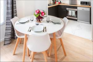 a white dining room table with white chairs and flowers at Casaminnie - Appartement à 8 min de Disneyland Paris in Bussy-Saint-Georges