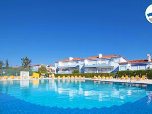 a large swimming pool with chairs and a building at Apartamento Oásis Parque 1 in Portimão