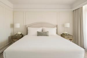 Un dormitorio con una gran cama blanca con dos mesitas de noche. en Corinthia Palace Malta, en Attard