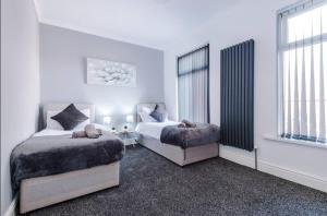 two beds in a bedroom with white walls and windows at Modern & Cozy 3BR House - Sleeps 8 in Golborne