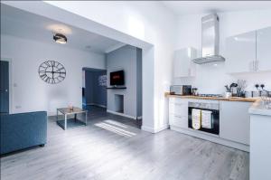 a large white kitchen with a table in the middle at Modern & Cozy 3BR House - Sleeps 8 in Golborne