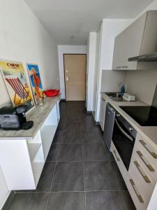 Una cocina con gabinetes blancos y piso de baldosas. en Studio spacieux en centre Ville, en Calvi