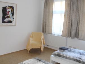 a bedroom with a yellow chair and a window at Haus Roy - Ferienwohnung Erdgeschoß in Zülpich +5 photos