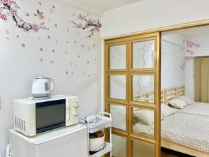 a room with a microwave and a bed with flowers on the wall at Shinjuku Wasedaハウス T4 in Tokyo