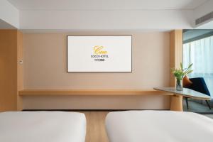 two beds in a room with a picture on the wall at Guangzhou Baiyun Airport COCO Hotel T2 Terminal Store Canton Fair Free Shuttle Bus in Huadu