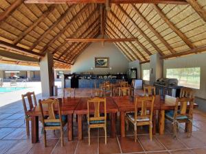 a dining room with a large wooden table and chairs at Thandolwami Bushlodge & Spa in Hoedspruit