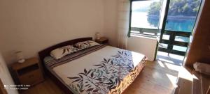 a bed in a room with a large window at Robinson Mili in Bogomolje