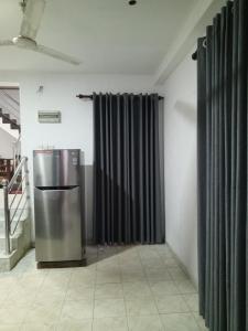 ein metallischer Kühlschrank in einem Raum mit schwarzen Vorhängen in der Unterkunft Villa Lumina Unawatuna in Galle
