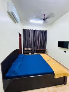 a bedroom with a blue bed and a tv at Hotel Garden View in Panaji