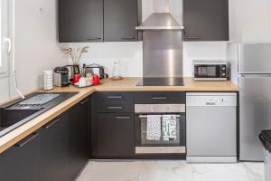 a kitchen with black cabinets and a stove top oven at Casaminnie - Appartement à 8 min de Disneyland Paris in Bussy-Saint-Georges