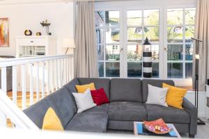 a living room with a gray couch with colorful pillows at Reethus WE 3, Blaumuschel in Borgsum