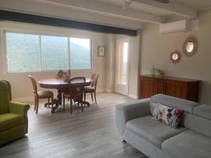 a living room with a table and a couch at Vacances de rêve vue mer et montagne in Brando