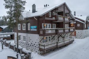 a large wooden house with snow on it at Levikaira Apartments - Alpine Chalets in Levi