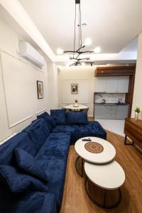 a living room with a blue couch and two tables at AXIOM Apartments - city center in Skopje