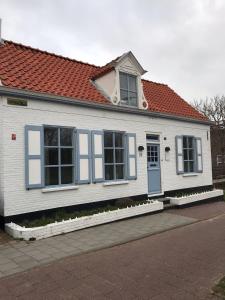 a white house with blue windows and a red roof at B&B Zee van Tijd Domburg in Domburg