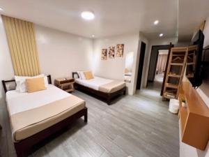 a room with two beds and a tv and a ladder at La Palme in El Nido