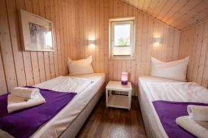 two beds in a small room with a window at Typ F "John Flint" -Kapitänshaus- in Pelzerhaken