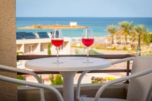 two glasses of wine sitting on a table on a balcony at Primavera Beach Hotel Studios & Apartments in Malia
