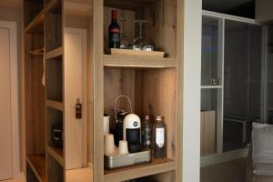 a cupboard with a coffee maker and bottles of alcohol at Savoy Beach Hotel & Thermal Spa in Bibione