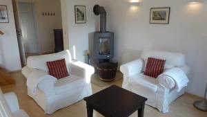 a living room with two white chairs and a stove at Galerie E MITTE in Gingst
