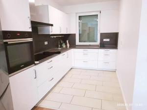 eine weiße Küche mit weißen Schränken und einem Fenster in der Unterkunft Neues 3ZimerHaus Düsseldorf Airport &Messe in Ratingen
