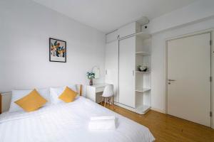 a white bedroom with a large white bed with orange pillows at Solena Landmark Riverside Apartment in Mậu Lâm (3)