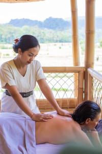 a woman giving a woman a back massage at Sidemen Luxury Nyan Bali - Bamboo House in Selat