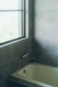 une baignoire dans une salle de bain avec une fenêtre dans l'établissement Atelier Hyakuna, à Nanjō 14 autres photos