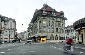 a person riding a bike down a street with a building at BANK House Studio L 205 - GRIWA RENT in Interlaken
