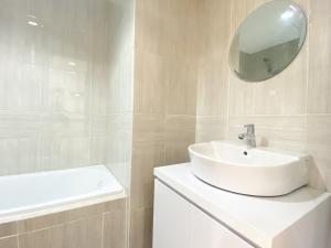 a white bathroom with a sink and a mirror at Homey and Elegant Studio Vasanta Innopark Apartment By Travelio in Cikarang
