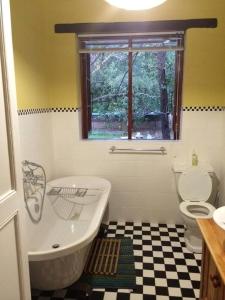 a bathroom with a white tub and a checkered floor at Murrayfield Karoo Guest Villa in Nieu-Bethesda +16 photos