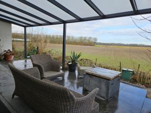 a patio with chairs and a table and a field at Sea Breeze apartment Hellevoetsluis in Hellevoetsluis