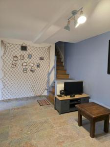 een woonkamer met een tv en een tafel en een trap bij Maison avec jardin et parking gratuit in Étretat