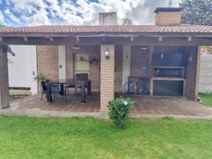einen Pavillon mit einem Tisch und Stühlen auf einer Backsteinterrasse in der Unterkunft Casa con quincho y pileta in Cordoba