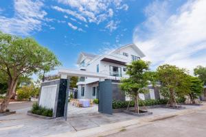 a white house with trees in front of it at Villa B2-34 Long Cung - 8 phòng ngủ - 100m tới biển in Vung Tau