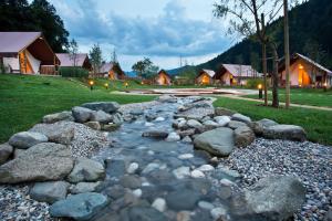een stroom rotsen in een tuin met huizen bij Herbal Glamping Resort Ljubno in Ljubno