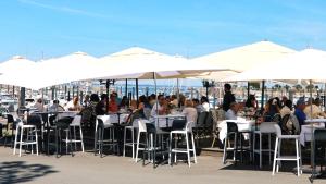 a group of people sitting at tables under white umbrellas at Résidence Les Suites du Port - by Le Saint Ferdinand in Arcachon