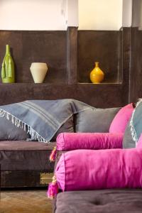 a couch with pink and grey pillows in a room at RIAD PRIVATIF avec Piscine Chauffée au Cœur de la Médina et Petits-Déjeuners Inclus in Marrakech