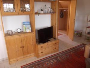 a living room with a television on a wooden cabinet at Finnhäuser am Vogelpark - Haus Luise in Marlow