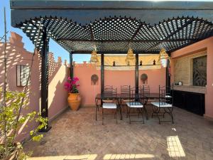 a patio with a table and chairs under a pergola at RIAD PRIVATIF avec Piscine Chauffée au Cœur de la Médina et Petits-Déjeuners Inclus in Marrakech