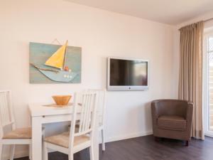 a living room with a table and a tv on the wall at Ferienwohnung Julian in Hörnum