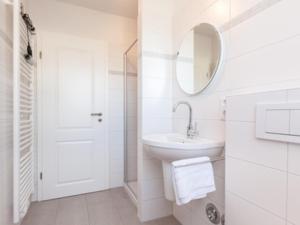 a white bathroom with a sink and a mirror at Ferienwohnung Julian in Hörnum +3 photos