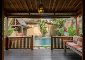 a porch with a bench and a swimming pool at Natajiwa Village in Seminyak