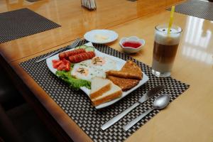 a plate of food with eggs and bread and a drink at Hotel SELFIE in Semey