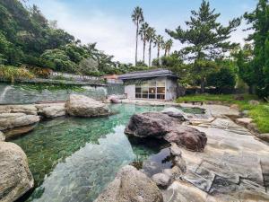 a pool of water with rocks in front of a house at Hotel Cetus Royal in Higashiizu
