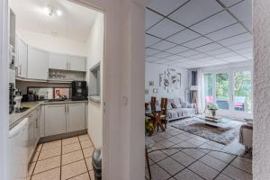 a kitchen with white cabinets and a living room at La Palmeraie 300m plage, calme in Arcachon