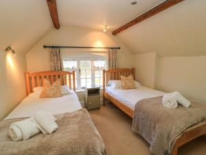 zwei Einzelbetten in einem Zimmer mit Fenster in der Unterkunft April Cottage in Chipping Campden