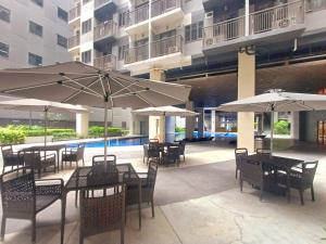 un patio avec tables et chaises avec parasols dans l'établissement My Staycation moa area S Residences tower1, à Manille