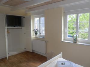 ein weißes Zimmer mit einem Bett und zwei Fenstern in der Unterkunft Lillebroo in Boldixum