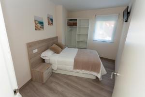 a small bedroom with a bed and a window at Apartamentos Raices in Cee